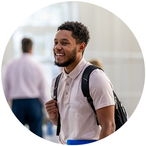 Student smiling wearing striped shirt and black back pack 