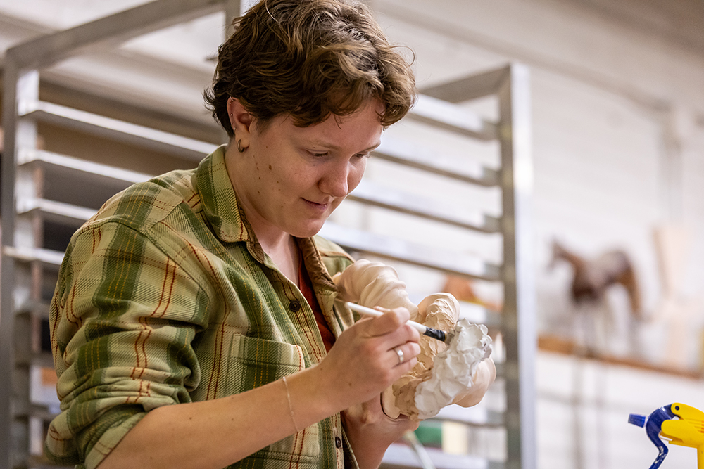 Student paiting ceramic item in art class