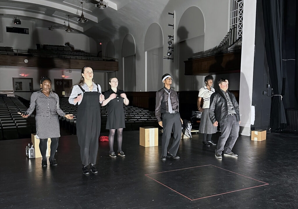 Performers on stage in all black during theatre performance of Interview