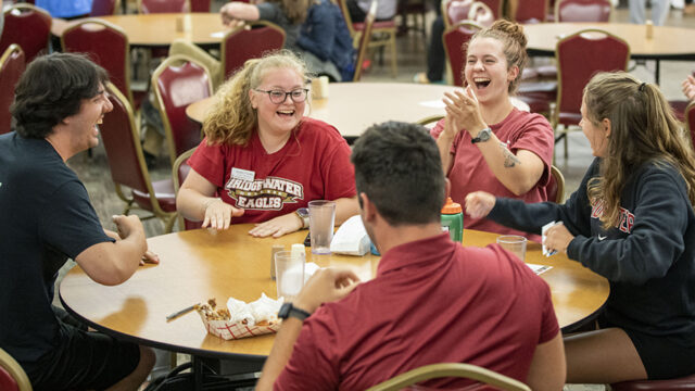 Students sitting at a dining table laughing and having fun