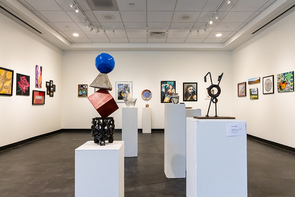 Art gallery with paintings on the back wall and sculptures scattered throughout the room in the foreground