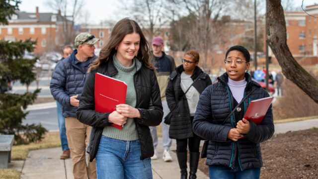 Two prospective students walking in the foreground with parents walking behind during campus tour