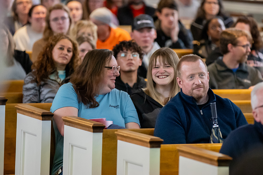 Mom and daughter sitting in pews smiling