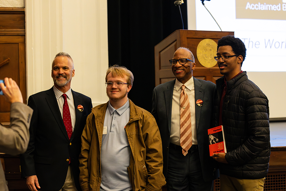 Dr. Bushman and Wil Haygood posing and smiling with two students for a photo