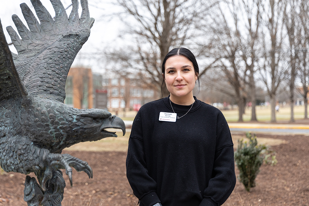 Hannah Barnes wearing black sweater standing next to Eagle statue