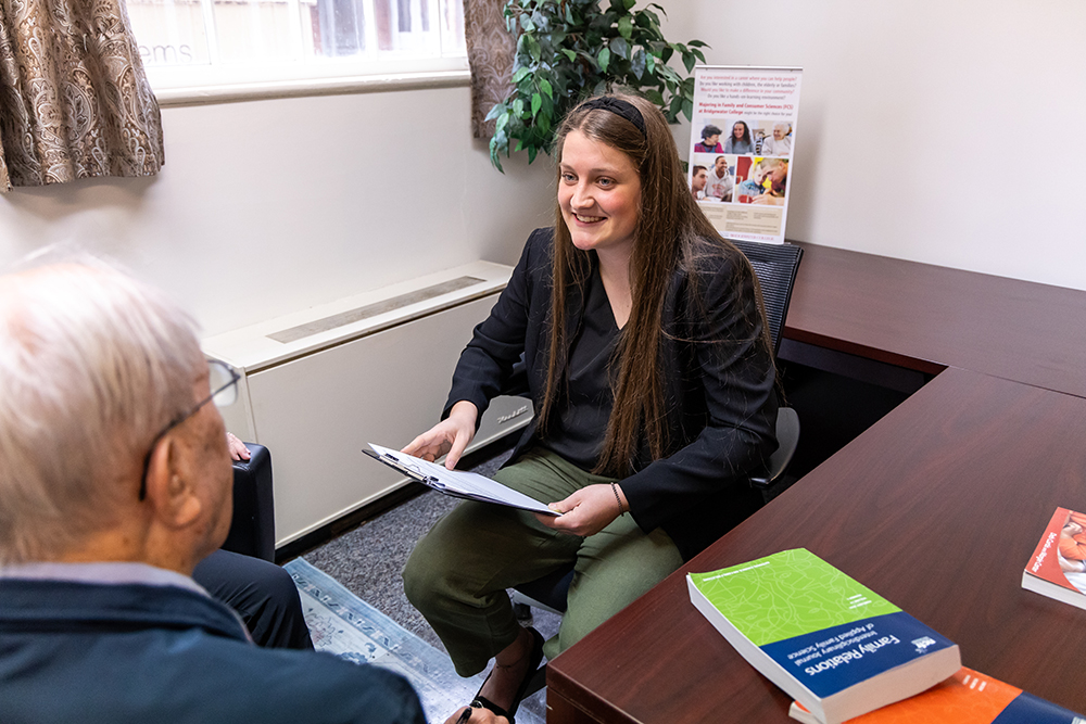 Person sitting at a desk talking to an elderly man