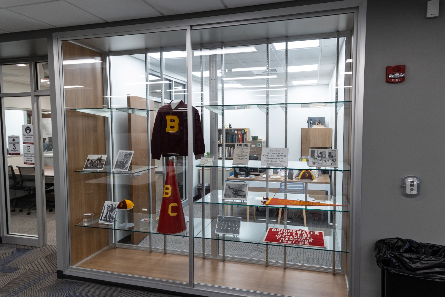 Glass display of historic Bridgewater sweater, megaphone, photos, and flags