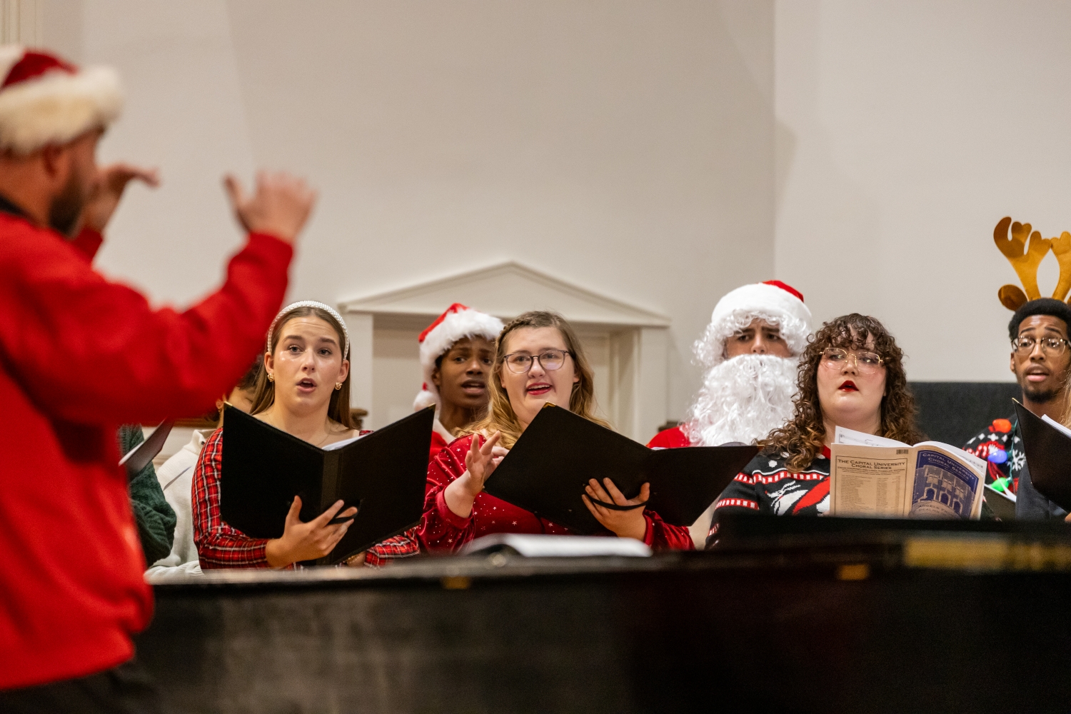 Students in holiday themed attire singing on stage